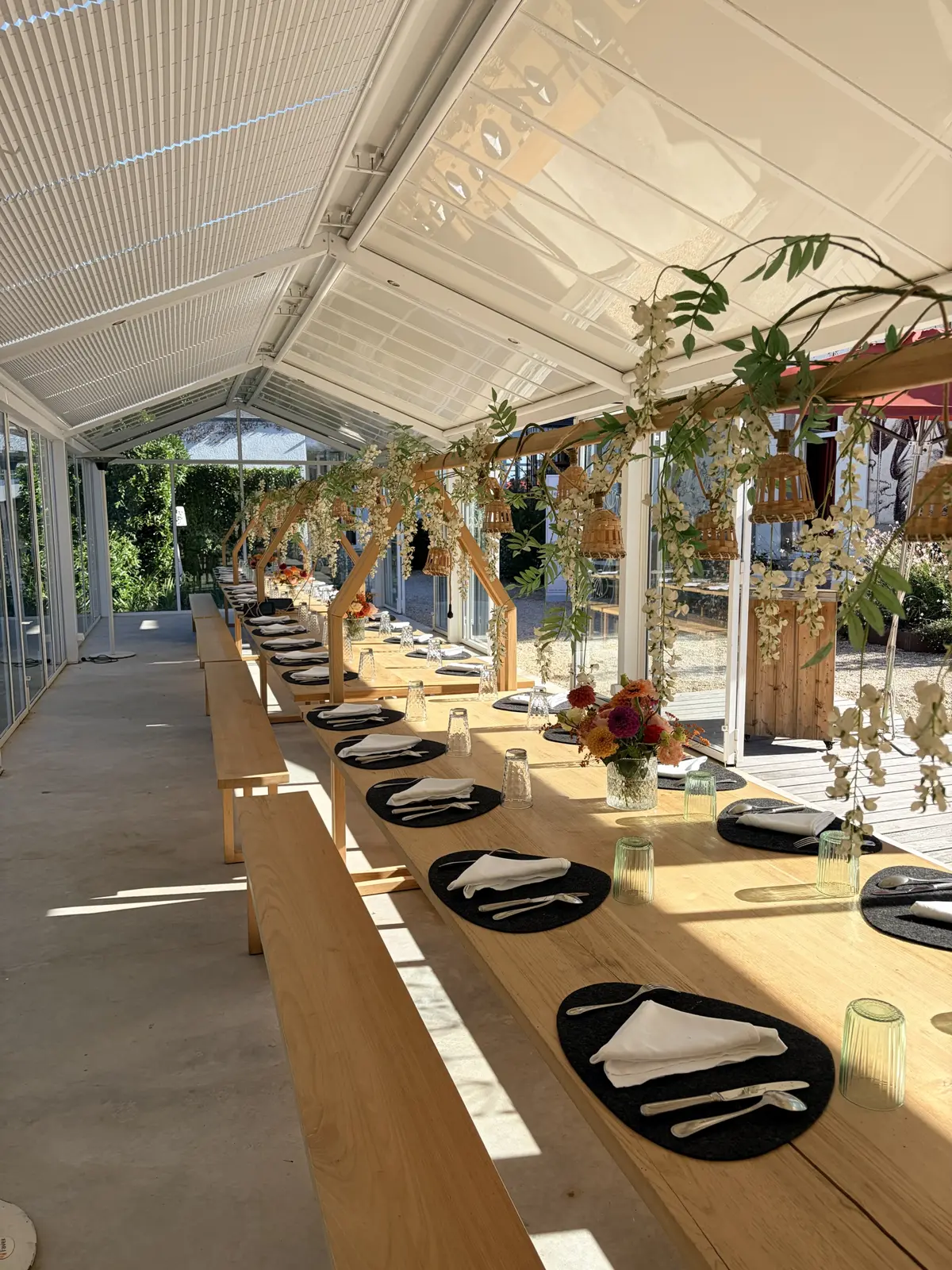 Grande table dressée sous une verrière fleurie